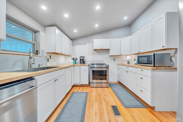 3554 Leffel Rd, Roanoke, VA 24018 - kitchen with appliances with stainless steel finishes, a sink, light wood-style floors, white cabinetry, and lofted ceiling