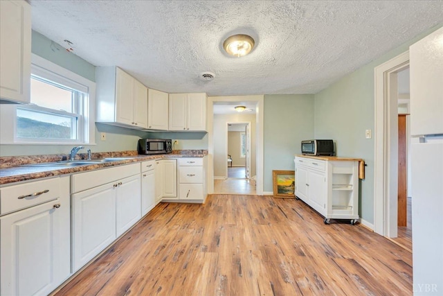 3554 Leffel Rd, Roanoke, VA 24018 - kitchen with stainless steel microwave, light wood-type flooring, white cabinets, a textured ceiling, and baseboards