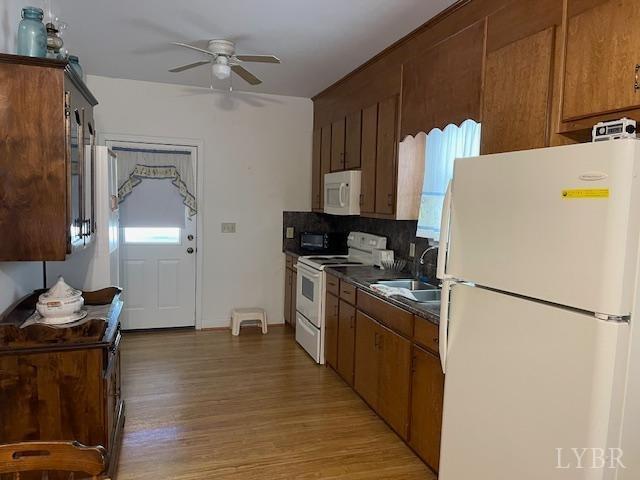1534 Main St, Altavista, VA 24517 - kitchen with a sink, dark countertops, a ceiling fan, white appliances, and light wood finished floors