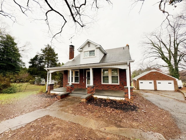 bungalow-style house with an outbuilding, a detached garage, a porch, brick siding, and a chimney