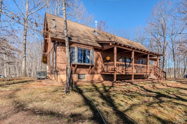 rear view of property featuring central air condition unit, a lawn, and roof with shingles
