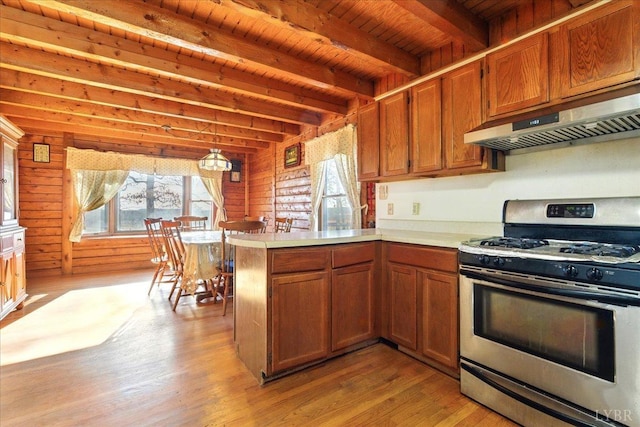kitchen with gas range, brown cabinetry, under cabinet range hood, and a peninsula