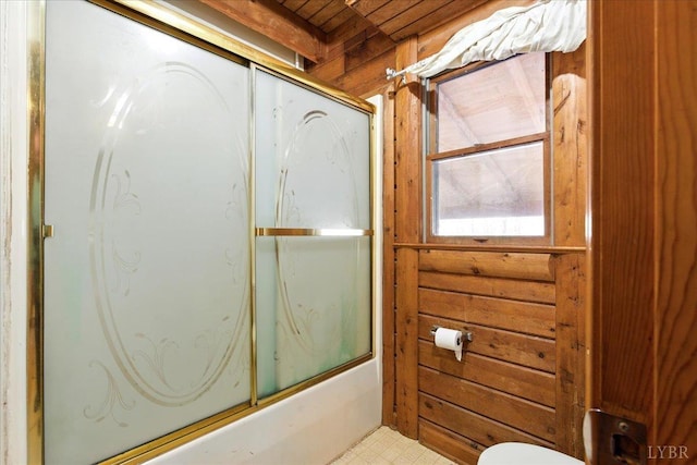 full bathroom featuring tile patterned floors, wooden walls, and toilet