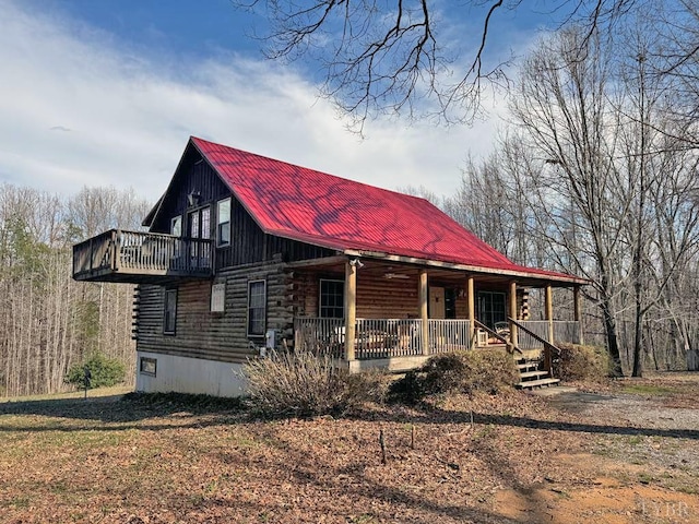 view of front facade featuring log siding, covered porch, and metal roof