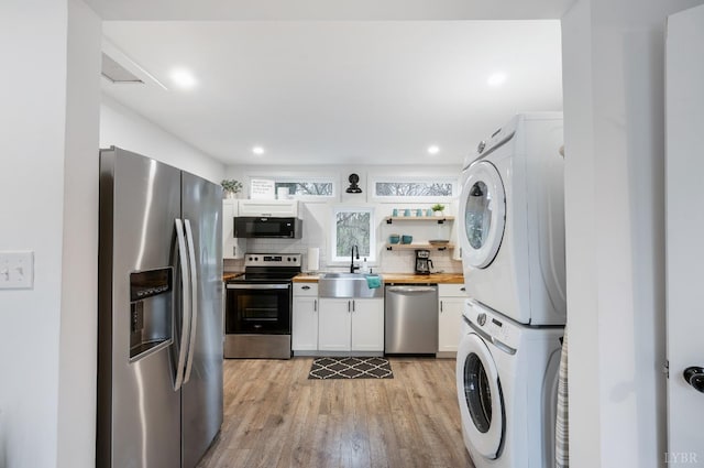 326 Jackson St, Lynchburg, VA 24504 - kitchen featuring a sink, appliances with stainless steel finishes, stacked washer / drying machine, white cabinetry, and light wood-style floors