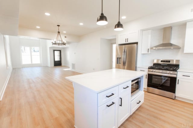 271 Riverside Dr, Lynchburg, VA 24503 - kitchen with wall chimney exhaust hood, appliances with stainless steel finishes, light countertops, light wood-type flooring, and decorative light fixtures