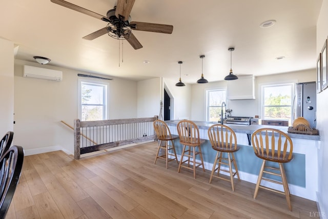 355 Camellia, Hurt, VA 24563 - kitchen with a wall unit AC, ceiling fan, light wood-type flooring, a breakfast bar, and freestanding refrigerator