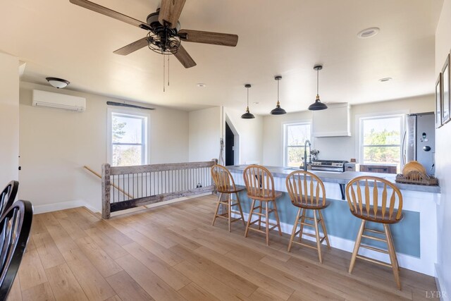 355 Camellia, Hurt, VA 24563 - kitchen with an AC wall unit, freestanding refrigerator, a breakfast bar area, light wood-style floors, and a ceiling fan