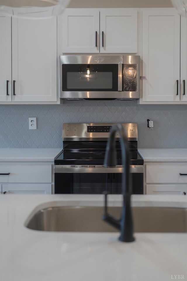 128 Brenleigh Ct Unit 102, Lynchburg, VA 24501 - kitchen with appliances with stainless steel finishes, light countertops, white cabinetry, and decorative backsplash