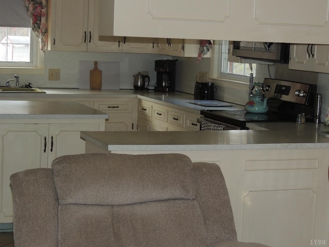 723 Custer Dr, Lynchburg, VA 24502 - kitchen with light countertops, backsplash, a sink, a peninsula, and appliances with stainless steel finishes
