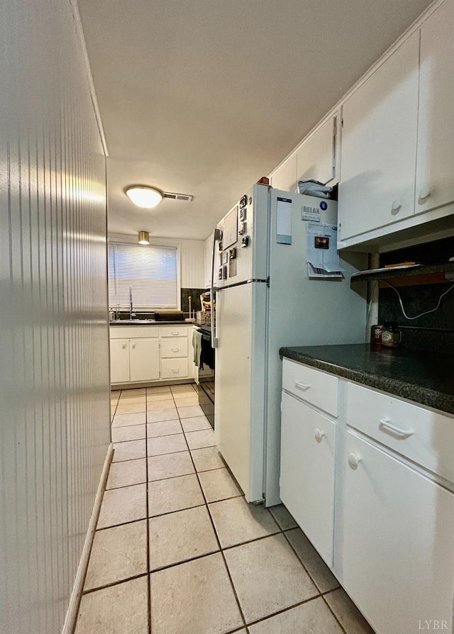 3101 Link Rd Unit 36, Lynchburg, VA 24503 - kitchen with dark countertops, light tile patterned floors, white cabinets, a sink, and freestanding refrigerator