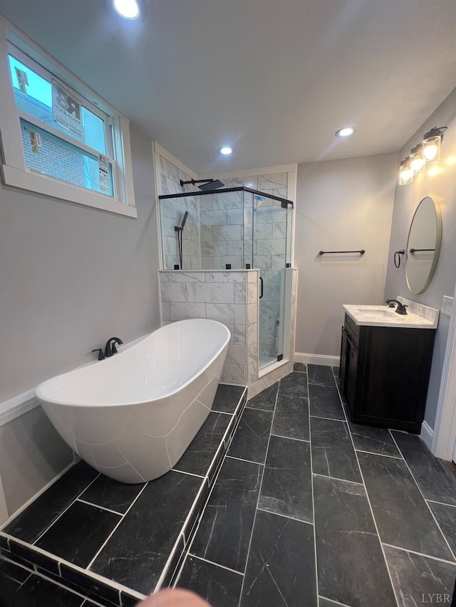 bathroom with vanity, marble finish floor, baseboards, a freestanding tub, and a stall shower