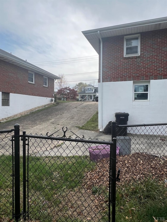 view of side of home featuring fence, a gate, and brick siding
