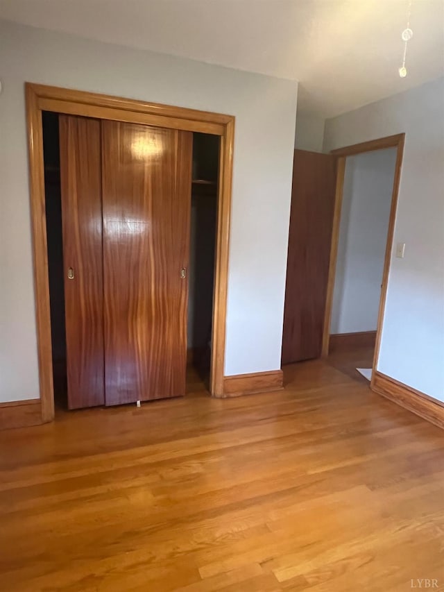 unfurnished bedroom featuring a closet, baseboards, and light wood finished floors
