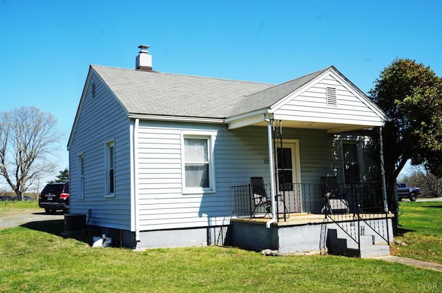 bungalow-style home with a front lawn, covered porch, and a chimney