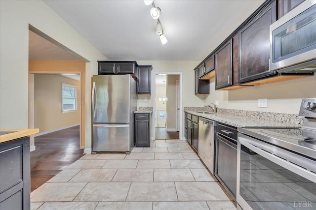 1048 Grove Ln, Roanoke, VA 24012 - kitchen with appliances with stainless steel finishes, a sink, dark brown cabinetry, light stone countertops, and baseboards