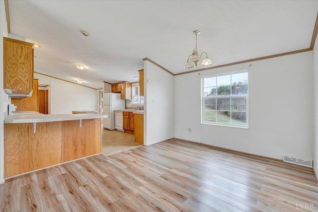 kitchen featuring plenty of natural light, white appliances, light wood-style flooring, visible vents, and lofted ceiling