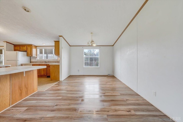 kitchen featuring freestanding refrigerator, light countertops, an inviting chandelier, and a wealth of natural light
