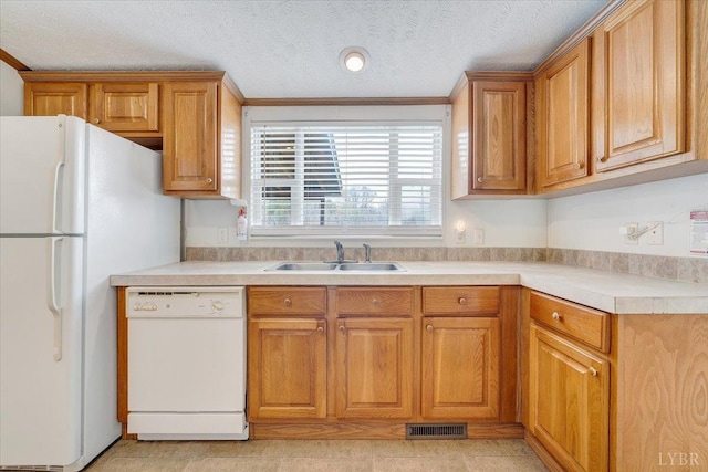 kitchen featuring visible vents, a sink, light countertops, white appliances, and brown cabinets