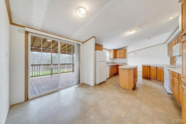 kitchen with white appliances, light countertops, a textured ceiling, and a kitchen island