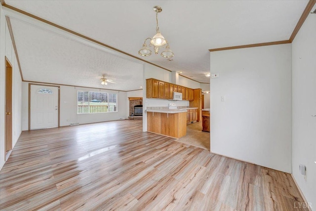 kitchen featuring open floor plan, crown molding, white microwave, and light wood-type flooring