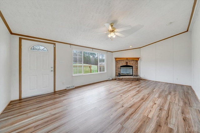 unfurnished living room featuring ornamental molding, a ceiling fan, light wood-style floors, and a textured ceiling