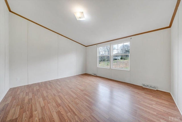 spare room with visible vents, vaulted ceiling, ornamental molding, and wood finished floors