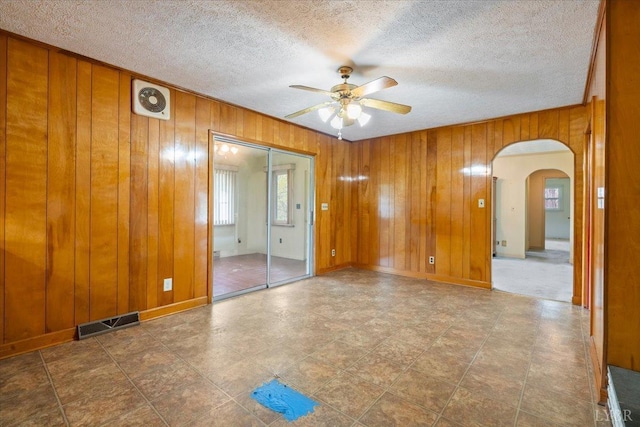 123 Knollwood Dr, Hurt, VA 24563 - unfurnished room with a ceiling fan, arched walkways, wooden walls, and a textured ceiling