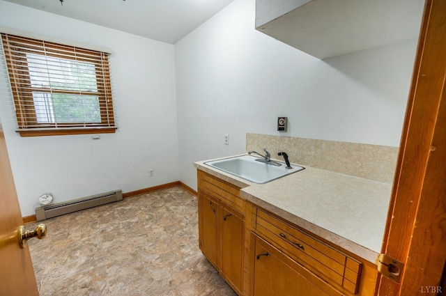 clothes washing area featuring a baseboard heating unit, a sink, and baseboards