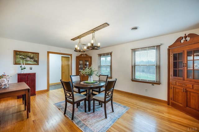 dining space with light wood-type flooring, a chandelier, and baseboards