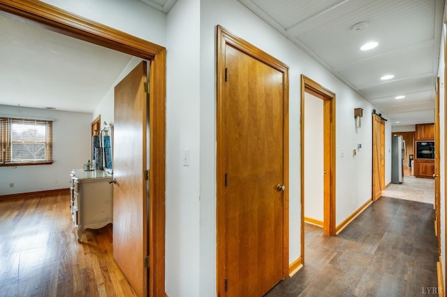 hallway with dark wood-style floors, baseboards, and recessed lighting