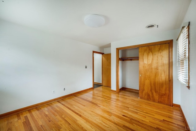 unfurnished bedroom with light wood finished floors, baseboards, and a closet