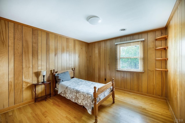 bedroom featuring light wood-style flooring, baseboards, and wood walls