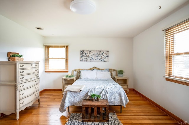bedroom featuring light wood finished floors, baseboards, and multiple windows