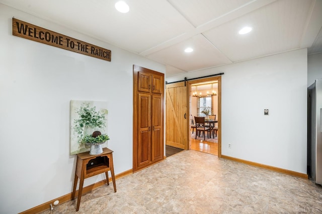 spare room with a barn door, recessed lighting, and baseboards