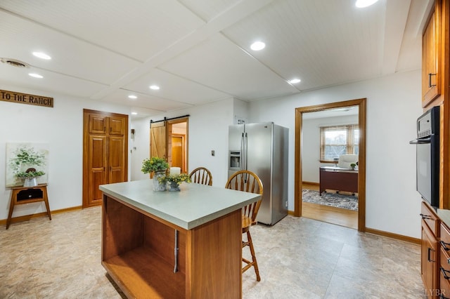 kitchen featuring stainless steel refrigerator with ice dispenser, black oven, a kitchen bar, a center island, and a desk