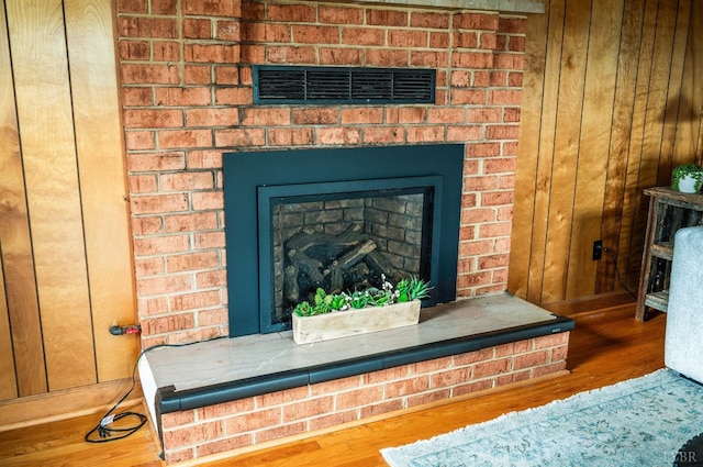 detailed view of wood finished floors, a fireplace, and wood walls