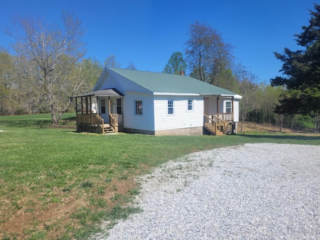 view of home's exterior with a lawn, driveway, a porch, and metal roof