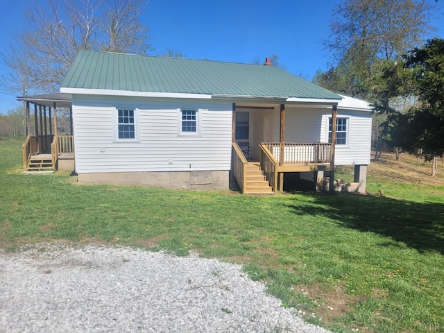 rear view of property with a lawn, covered porch, and metal roof