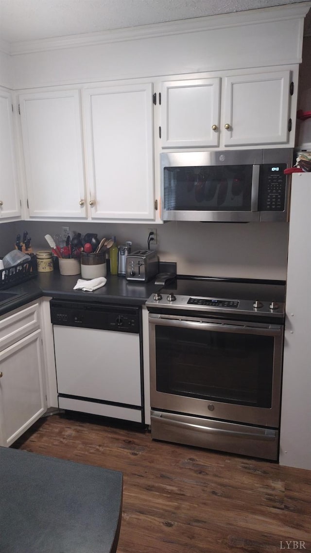 618 Prospect Rd, Hurt, VA 24563 - kitchen featuring crown molding, dark wood-type flooring, dark countertops, white cabinets, and appliances with stainless steel finishes