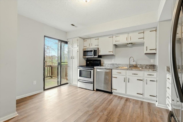 43 Nags Head Ct, Lynchburg, VA 24502 - kitchen with appliances with stainless steel finishes, a sink, light wood-type flooring, white cabinetry, and a textured ceiling