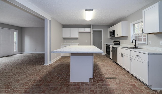 108 Trapper Ln, Vinton, VA 24179 - kitchen with stainless steel appliances, a sink, brick flooring, a center island, and a textured ceiling