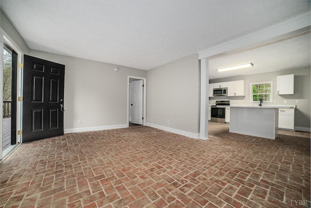 108 Trapper Ln, Vinton, VA 24179 - unfurnished living room featuring brick floors, baseboards, a sink, and a textured ceiling