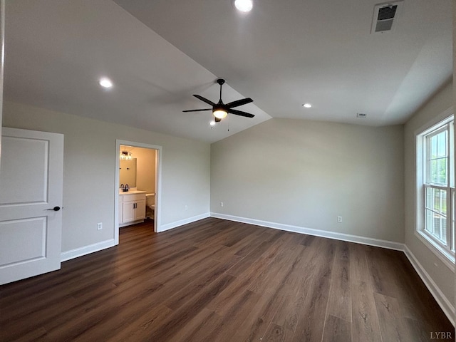 spare room featuring a ceiling fan, visible vents, dark wood-type flooring, and vaulted ceiling