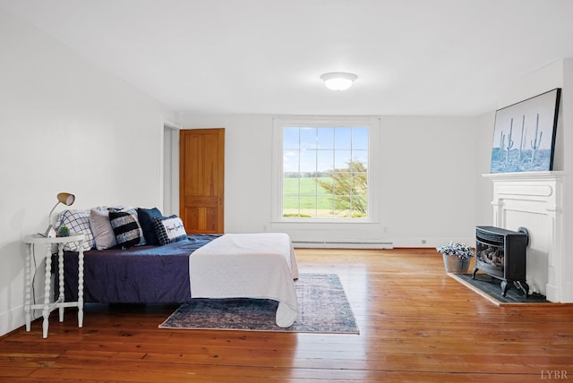 281 Calohan Rd, Rustburg, VA 24588 - bedroom with a wood stove, hardwood / wood-style flooring, and a baseboard heating unit