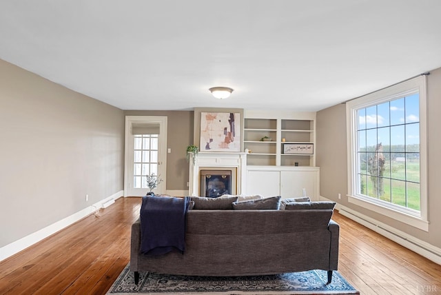 281 Calohan Rd, Rustburg, VA 24588 - living area featuring a baseboard radiator, a glass covered fireplace, baseboards, and hardwood / wood-style flooring