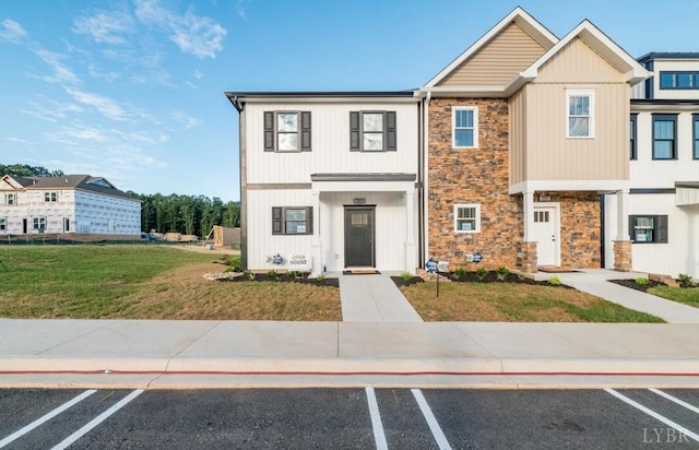 townhome / multi-family property featuring a front yard, stone siding, and uncovered parking