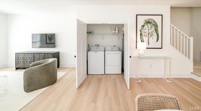 washroom with washing machine and clothes dryer, baseboards, wood finished floors, and laundry area