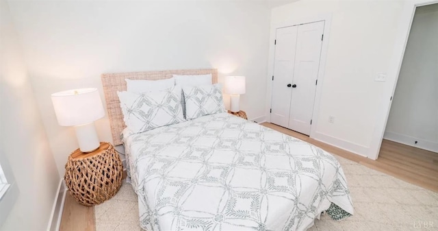bedroom featuring baseboards, wood finished floors, and a closet