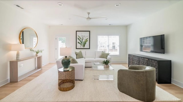 living room featuring light wood-style flooring, baseboards, a wealth of natural light, and ceiling fan